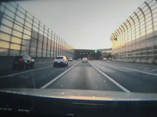 A woman standing on a highway soundproof tunnel. "Is it a ghost?" Hot Topic (upp